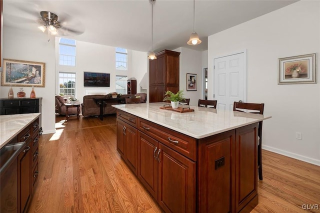 kitchen with decorative light fixtures, light hardwood / wood-style floors, a breakfast bar area, and a center island