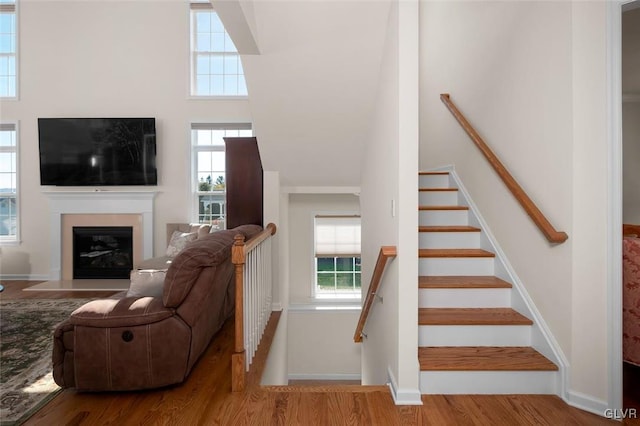 stairway with wood-type flooring and a high ceiling