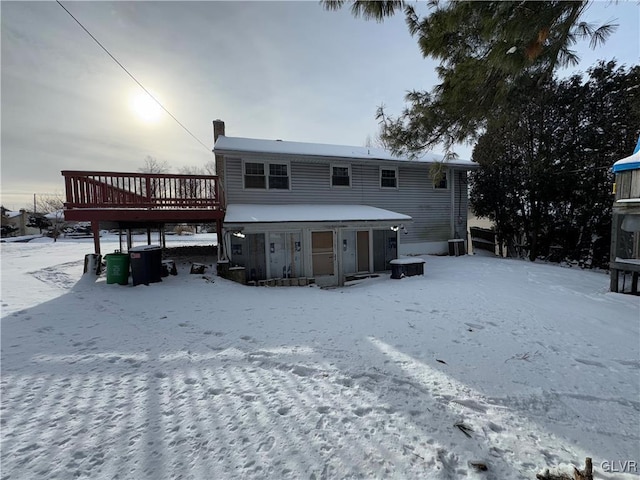 snow covered back of property with a wooden deck