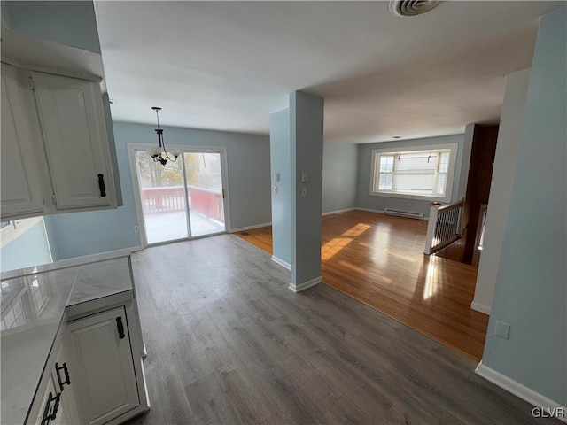 interior space featuring decorative light fixtures, white cabinetry, an inviting chandelier, and light wood-type flooring