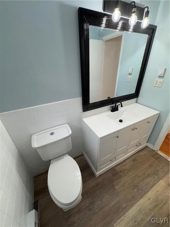 bathroom with vanity, hardwood / wood-style flooring, tile walls, and toilet