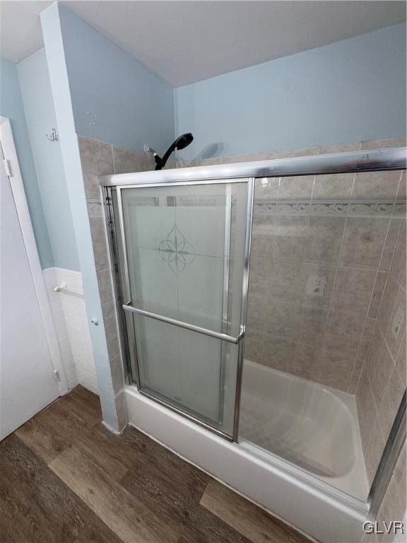 bathroom with hardwood / wood-style flooring, tile walls, and walk in shower