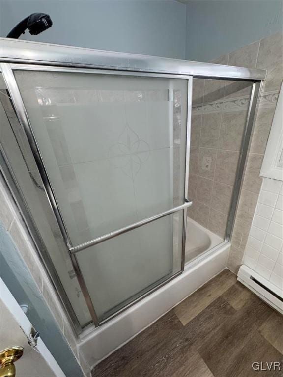 bathroom featuring a baseboard radiator, hardwood / wood-style flooring, and shower / bath combination with glass door