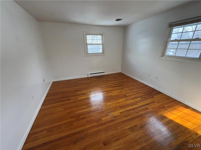 empty room featuring a wealth of natural light, a baseboard radiator, and dark hardwood / wood-style flooring