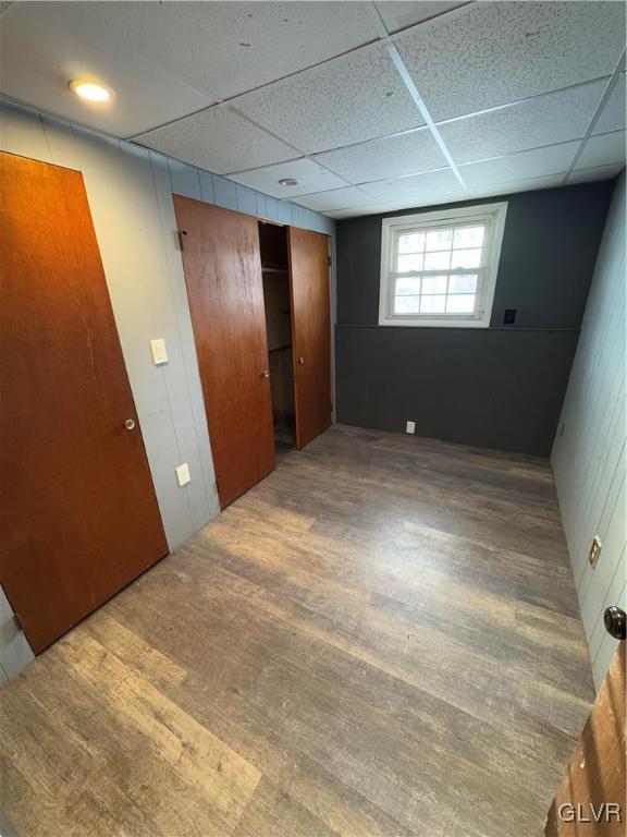 unfurnished bedroom featuring wood-type flooring and a drop ceiling