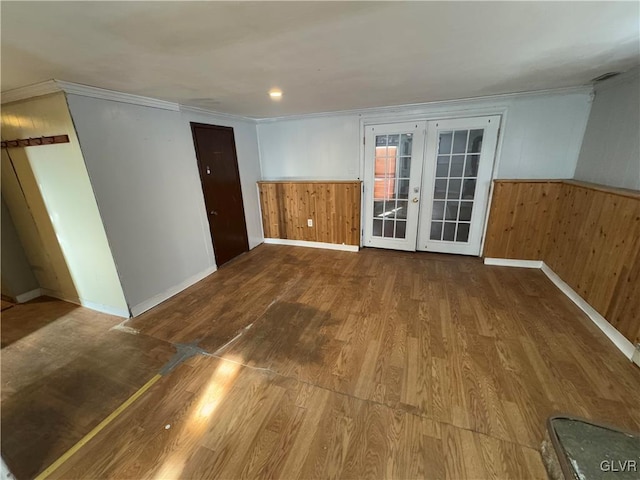 unfurnished room with hardwood / wood-style flooring, french doors, wood walls, and crown molding