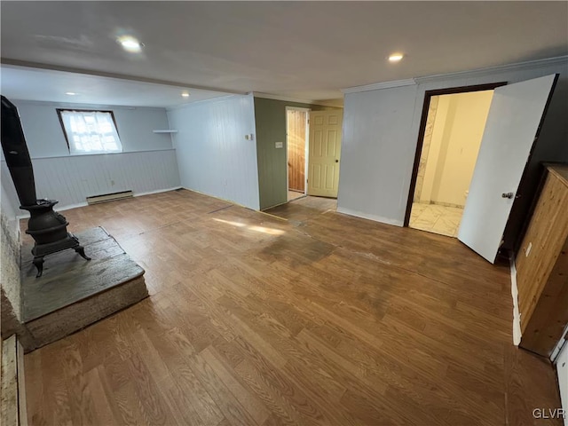 basement featuring hardwood / wood-style floors, a baseboard radiator, and crown molding