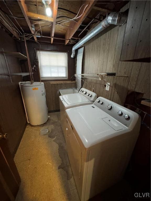 washroom featuring washing machine and dryer, wood walls, and water heater