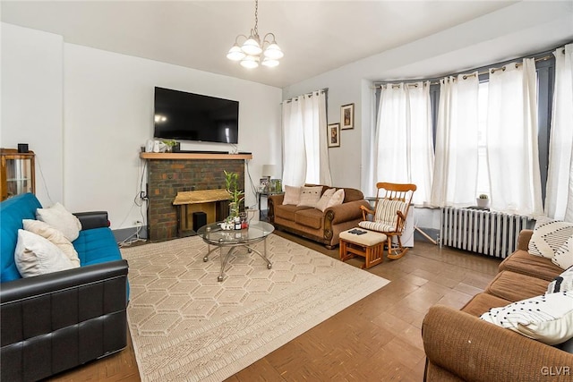 living room featuring a fireplace, radiator heating unit, an inviting chandelier, and wood-type flooring