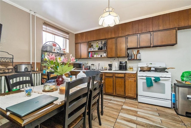 kitchen with crown molding, white range with gas cooktop, sink, and pendant lighting