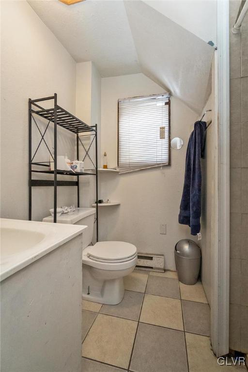 bathroom featuring toilet, a baseboard radiator, tile patterned floors, vanity, and vaulted ceiling