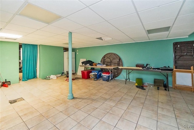 basement featuring fridge and a paneled ceiling