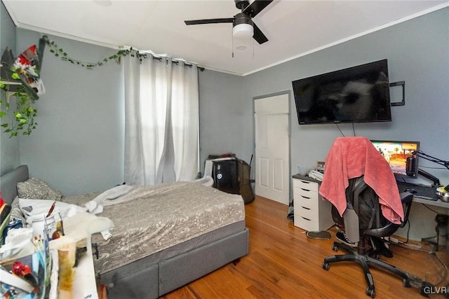 bedroom with hardwood / wood-style floors, ceiling fan, and ornamental molding