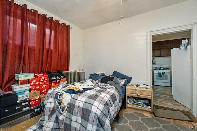 bedroom with wood-type flooring and white fridge