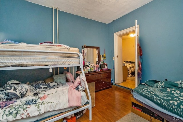 bedroom featuring lofted ceiling, a textured ceiling, and wood-type flooring