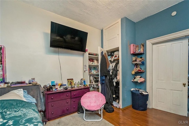 bedroom with hardwood / wood-style flooring, a textured ceiling, and a closet