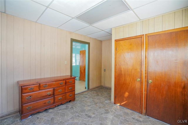 bedroom featuring wood walls and a paneled ceiling