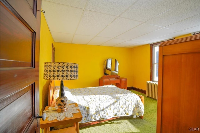 bedroom with carpet floors, radiator, and a paneled ceiling