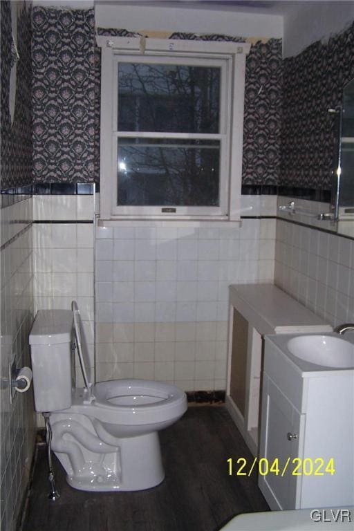 bathroom with wood-type flooring, tile walls, toilet, and vanity