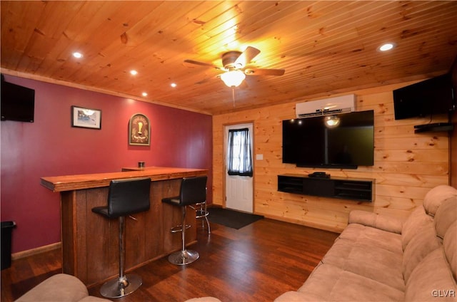 living room with dark wood-type flooring, wood walls, a wall mounted AC, ceiling fan, and bar area