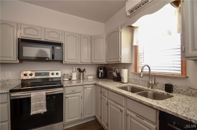 kitchen featuring black appliances, an AC wall unit, white cabinets, sink, and light stone counters