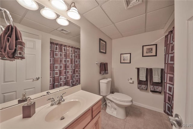 bathroom with a drop ceiling, toilet, vanity, and tile patterned flooring