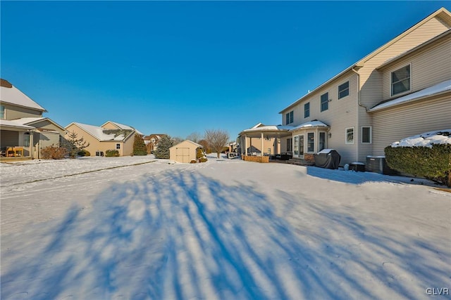 yard covered in snow with central air condition unit and a storage unit