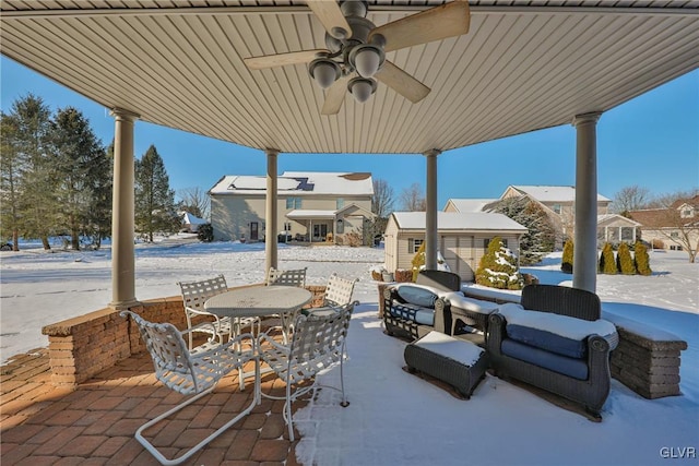 snow covered patio with ceiling fan and an outdoor structure