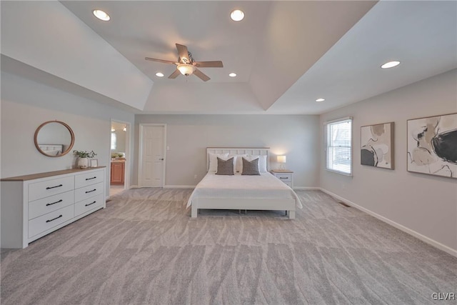 unfurnished bedroom featuring ceiling fan, light colored carpet, ensuite bathroom, and a raised ceiling