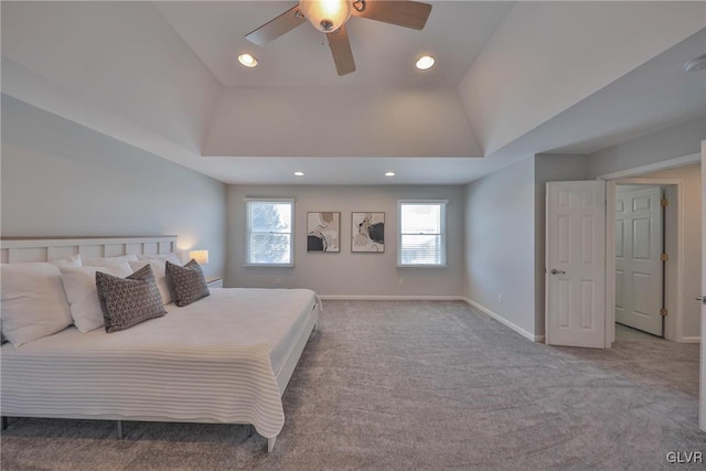 bedroom featuring ceiling fan, a tray ceiling, and light carpet