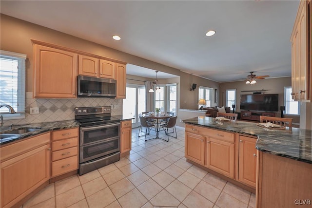 kitchen featuring hanging light fixtures, appliances with stainless steel finishes, sink, light tile patterned floors, and decorative backsplash