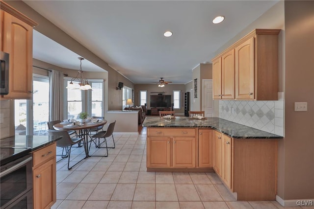 kitchen with dark stone counters, hanging light fixtures, kitchen peninsula, and decorative backsplash