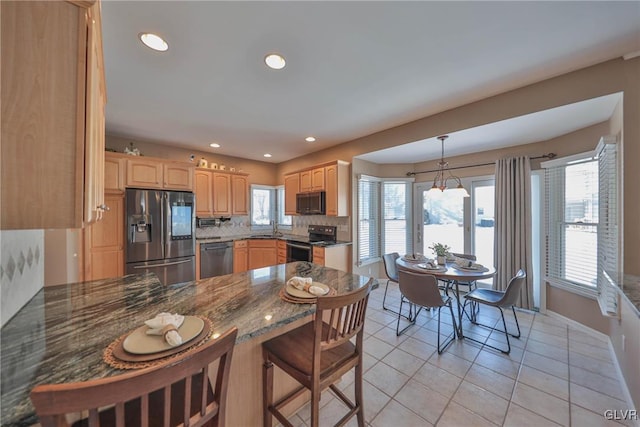 kitchen with a wealth of natural light, light tile patterned floors, decorative light fixtures, backsplash, and stainless steel appliances