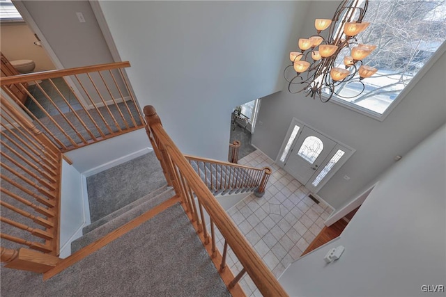 carpeted entrance foyer with a high ceiling and a chandelier