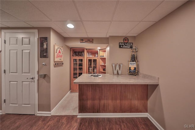 bar with sink, wood-type flooring, and a paneled ceiling