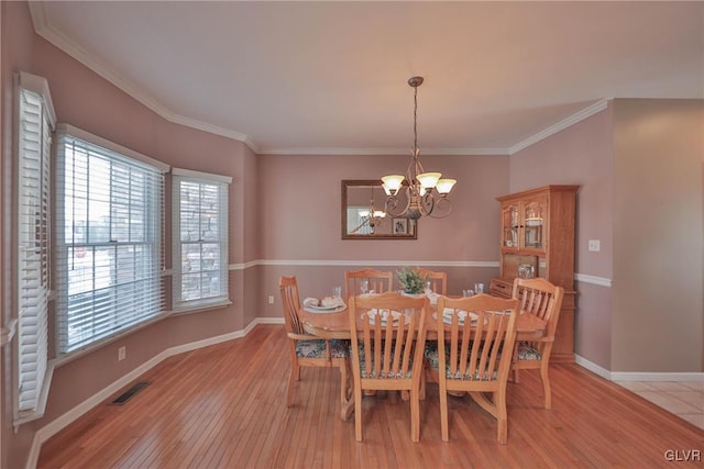 dining space featuring crown molding, light hardwood / wood-style floors, and an inviting chandelier