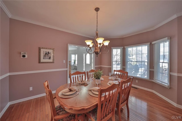 dining room featuring light hardwood / wood-style flooring, crown molding, and a chandelier