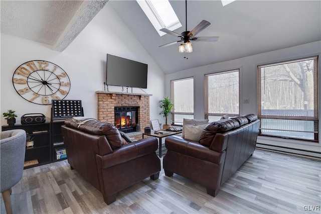 living room featuring a textured ceiling, wood-type flooring, a skylight, a fireplace, and high vaulted ceiling