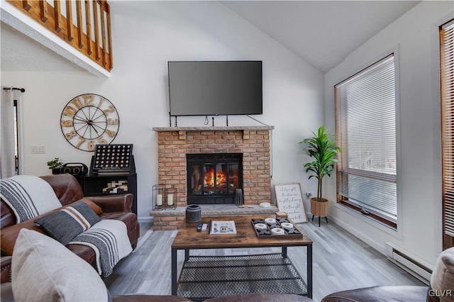 living room featuring wood-type flooring, a baseboard heating unit, lofted ceiling, and a fireplace