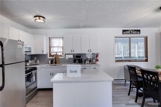 kitchen with sink, stainless steel appliances, a center island, and white cabinets