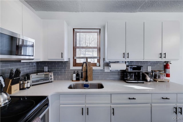 kitchen with decorative backsplash, sink, white cabinetry, and stainless steel appliances