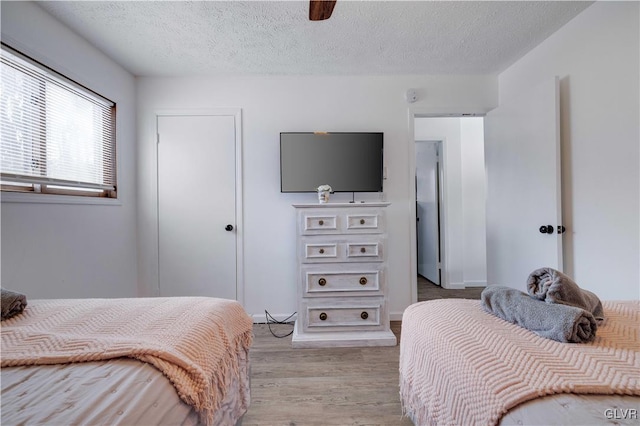 bedroom with ceiling fan, light hardwood / wood-style floors, and a textured ceiling