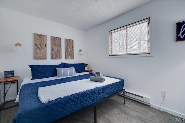 bedroom with baseboard heating, hardwood / wood-style flooring, and a textured ceiling