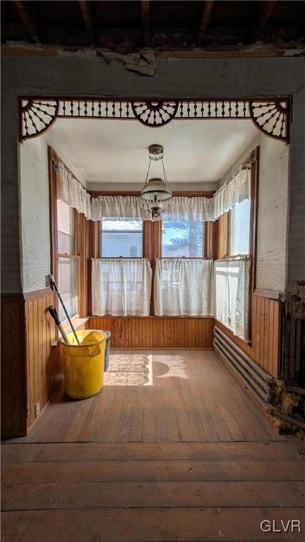 misc room featuring a notable chandelier, wood-type flooring, and wood walls