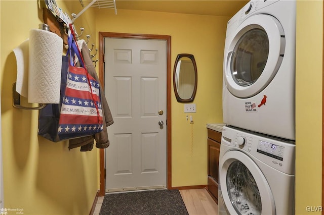 laundry area with light hardwood / wood-style floors and stacked washing maching and dryer