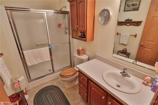 bathroom featuring vanity, toilet, and a shower with door