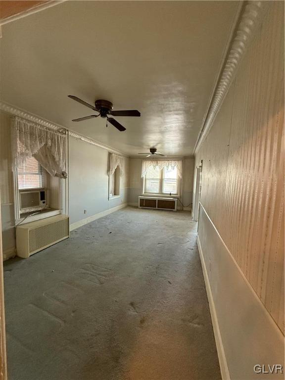 carpeted spare room with cooling unit, ceiling fan, and crown molding