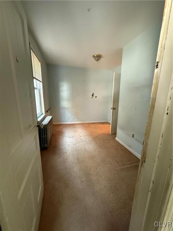 carpeted spare room featuring radiator heating unit