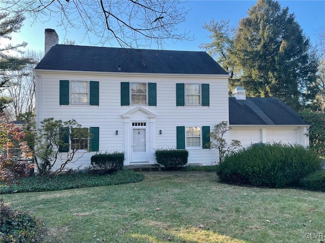 colonial-style house featuring a garage and a front lawn