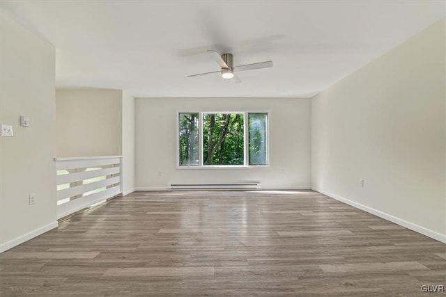 spare room with ceiling fan, light wood-type flooring, and a baseboard heating unit